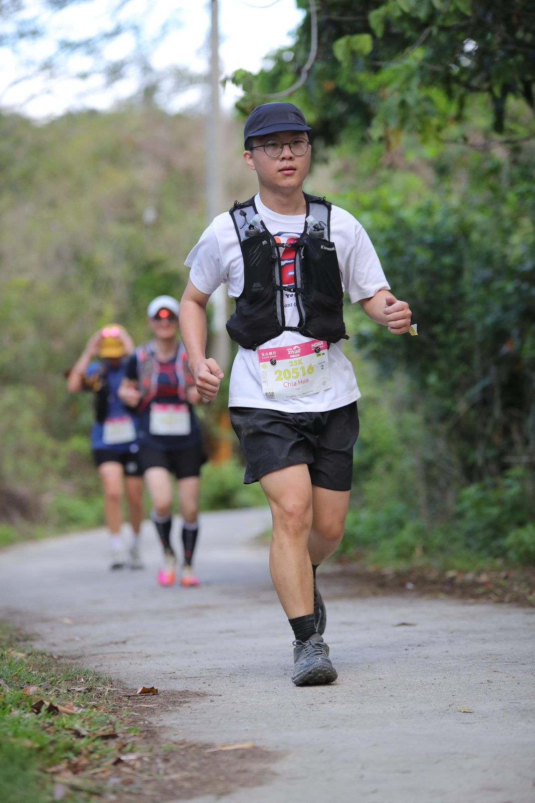 穿越野跑背心在林道路線上向前跑的人